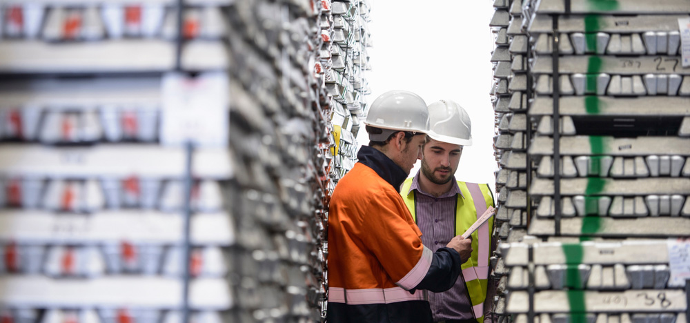 Image of two men with hard hats and high vis jackets, looking at a clipboard